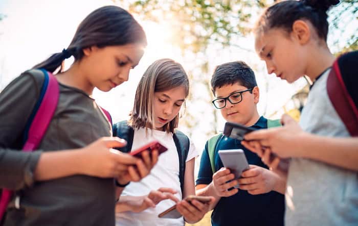 crianças usando smartphone nas escolas